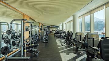 Uma academia com diversos equipamentos de exercício, janelas amplas e um teto com design ondulado.