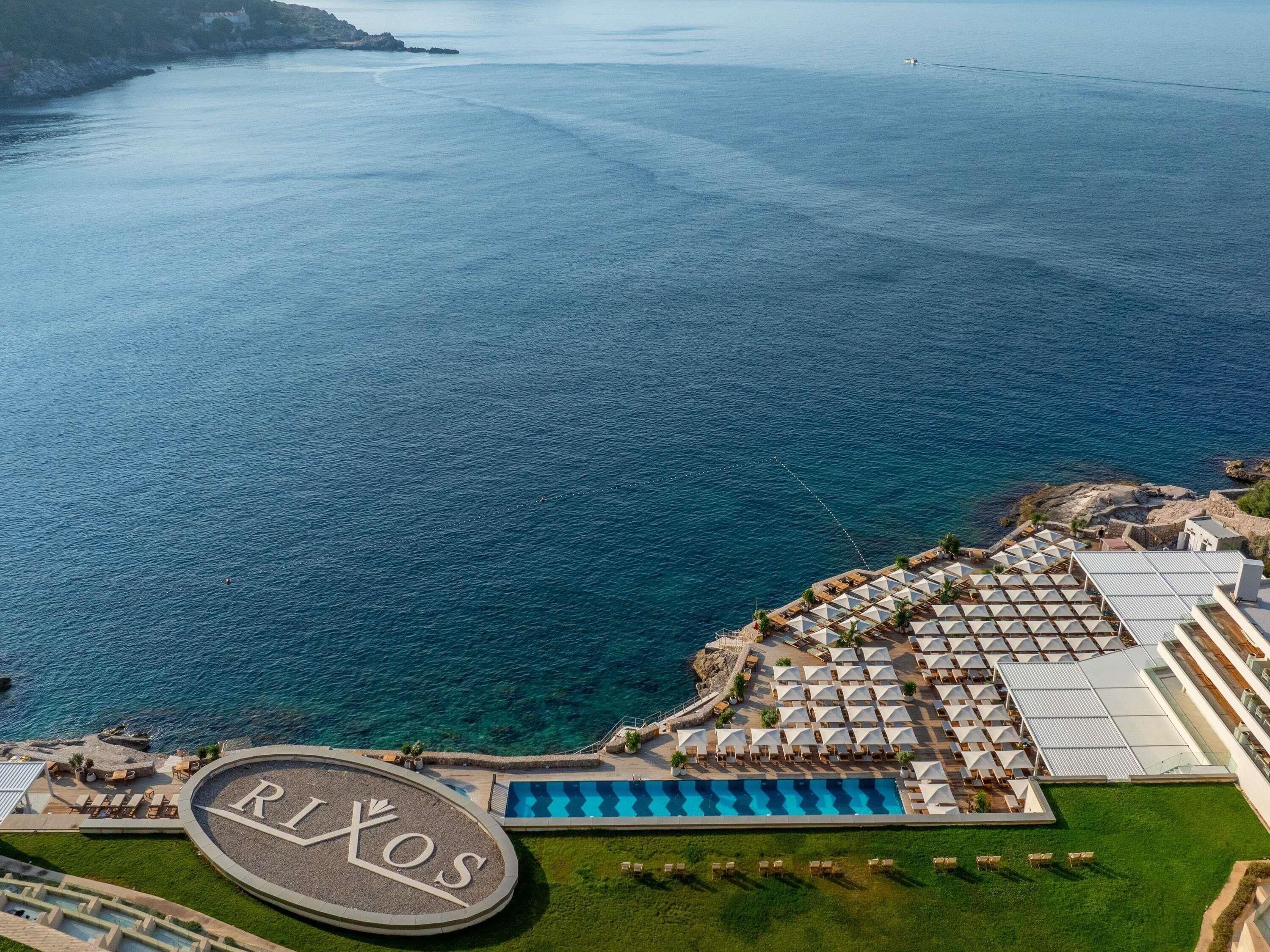 An aerial view of a resort with a pool, sun loungers, and a large sign with 'RIXOS' on it.