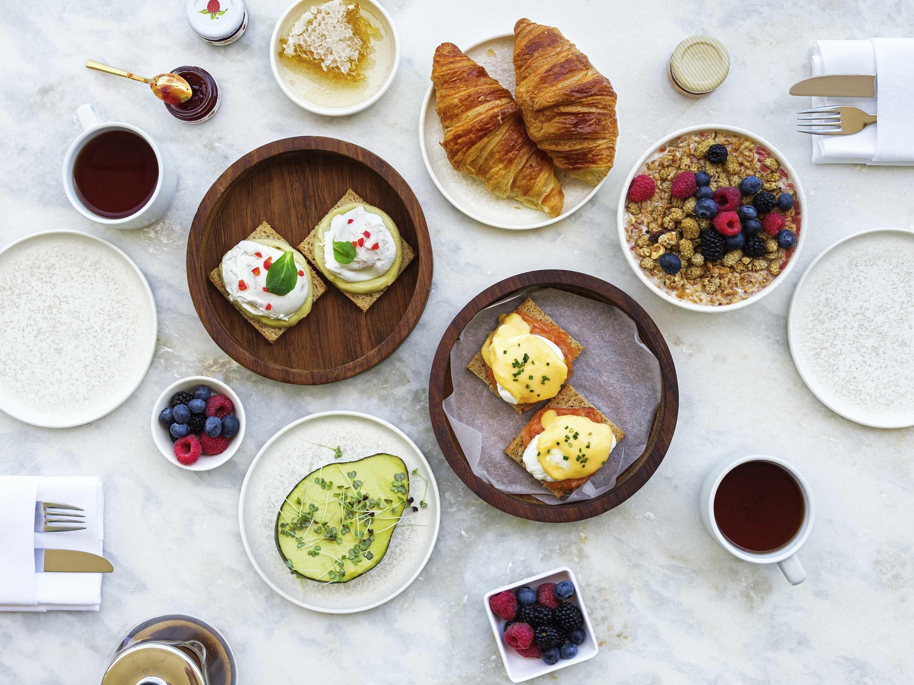 Ein Frühstückstisch mit Croissants, Toast mit Sahne, Beeren und Kaffee.