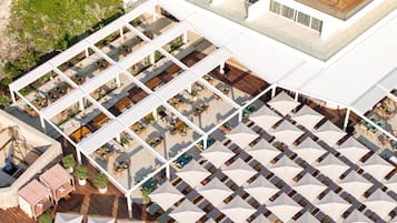 An aerial view of a hotel with multiple outdoor seating areas, including tables and chairs, arranged in a grid pattern.
