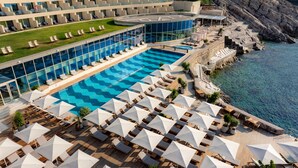 Un resort con una gran piscina, tumbonas y vista al mar.