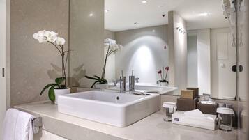 A modern bathroom with a large sink, two mirrors, and a shower.