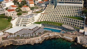 Un hotel frente al mar con una piscina grande, varios balcones y vistas al océano.
