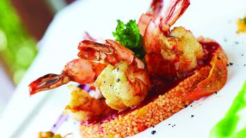 A plate of grilled shrimp with a side of vegetables and a decorative garnish.