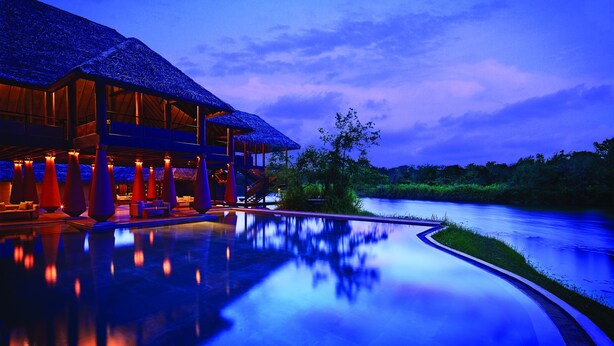 A resort with a pool reflecting the building and a river. - Jetwing Vil Uyana, A Luxury Reserve (Sigiriya)