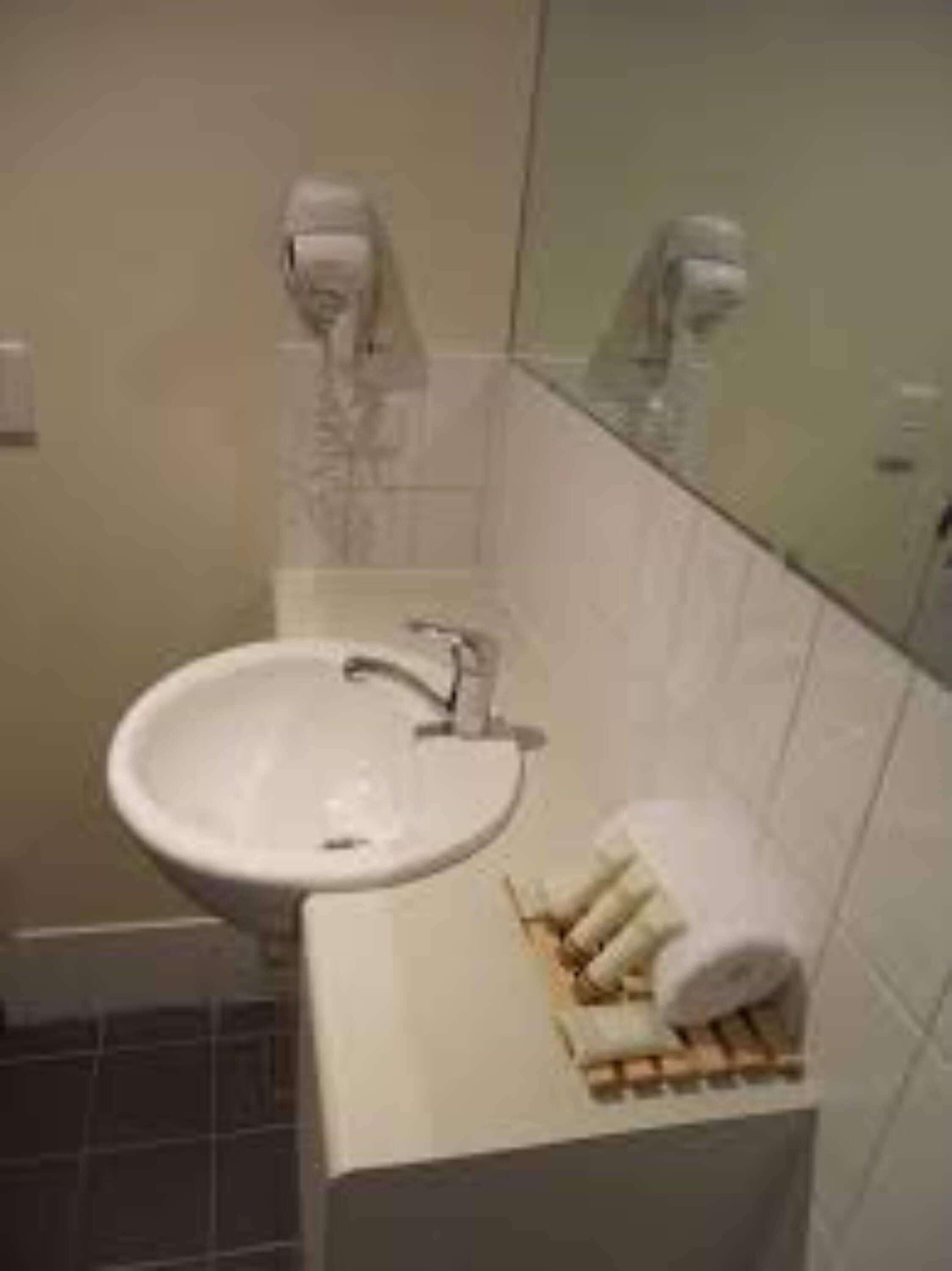 A bathroom with a white sink, a mirror, and a towel rack with towels.