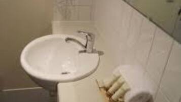 A bathroom with a white sink, a mirror, and a towel rack with towels.