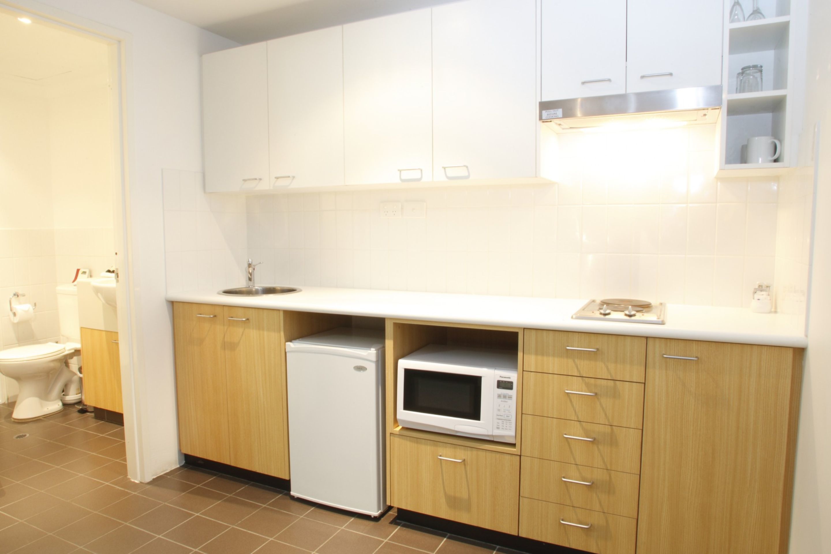 A modern kitchen with white cabinets, a microwave, and a refrigerator.