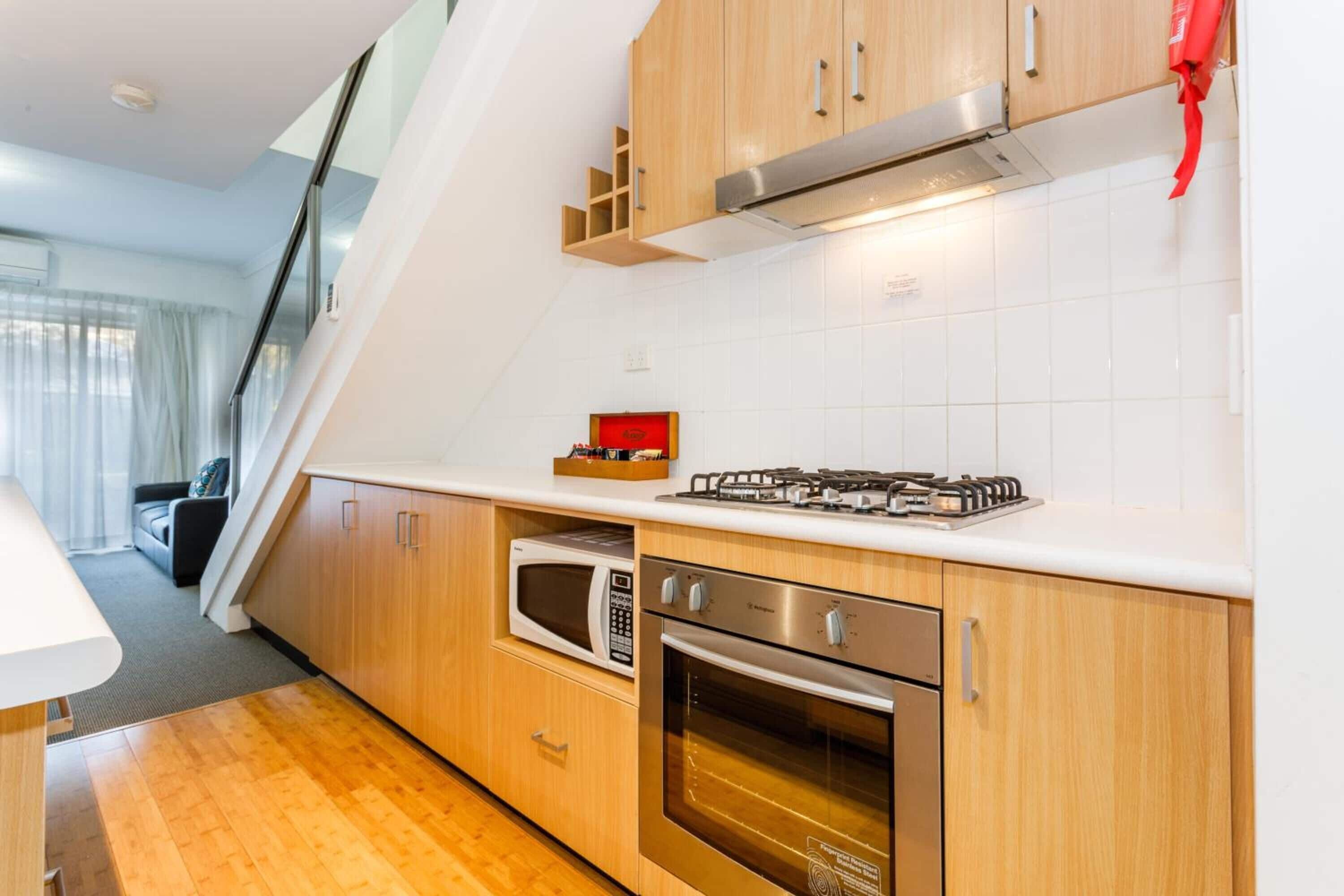 A modern kitchen with wooden cabinets, a gas stove, a microwave, and an oven.