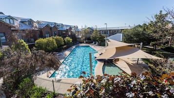 Una piscina al aire libre, sombrillas, sillones reclinables de piscina