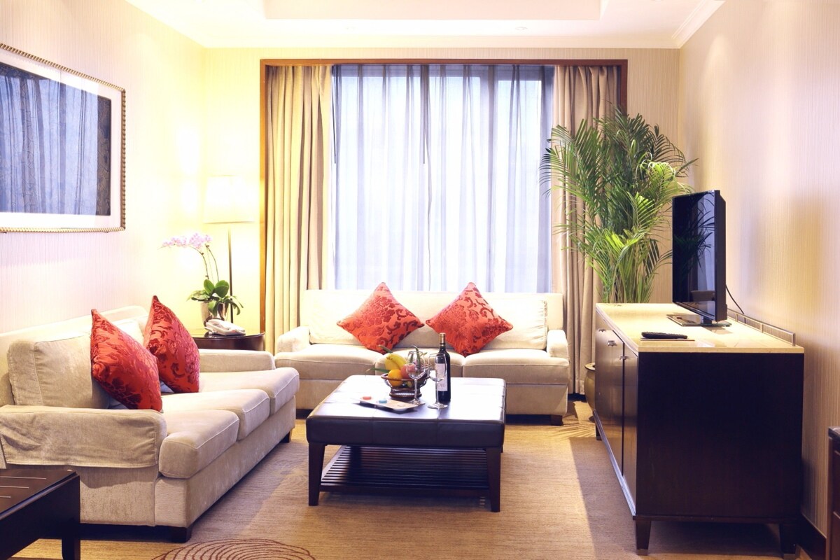 Una sala de estar con sofá, mesa de centro y mueble para televisor.