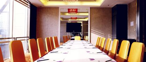 A conference room with a long table, yellow chairs, and a chandelier.
