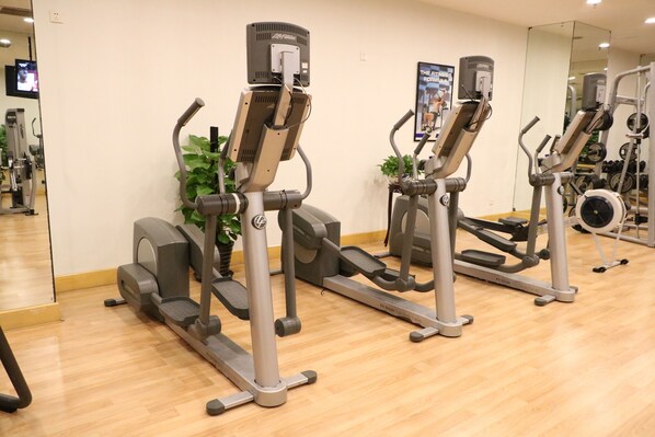 A gym with stationary bikes, a treadmill, and a mirrored wall. - Grand Mercure Beijing Central (Beijing)