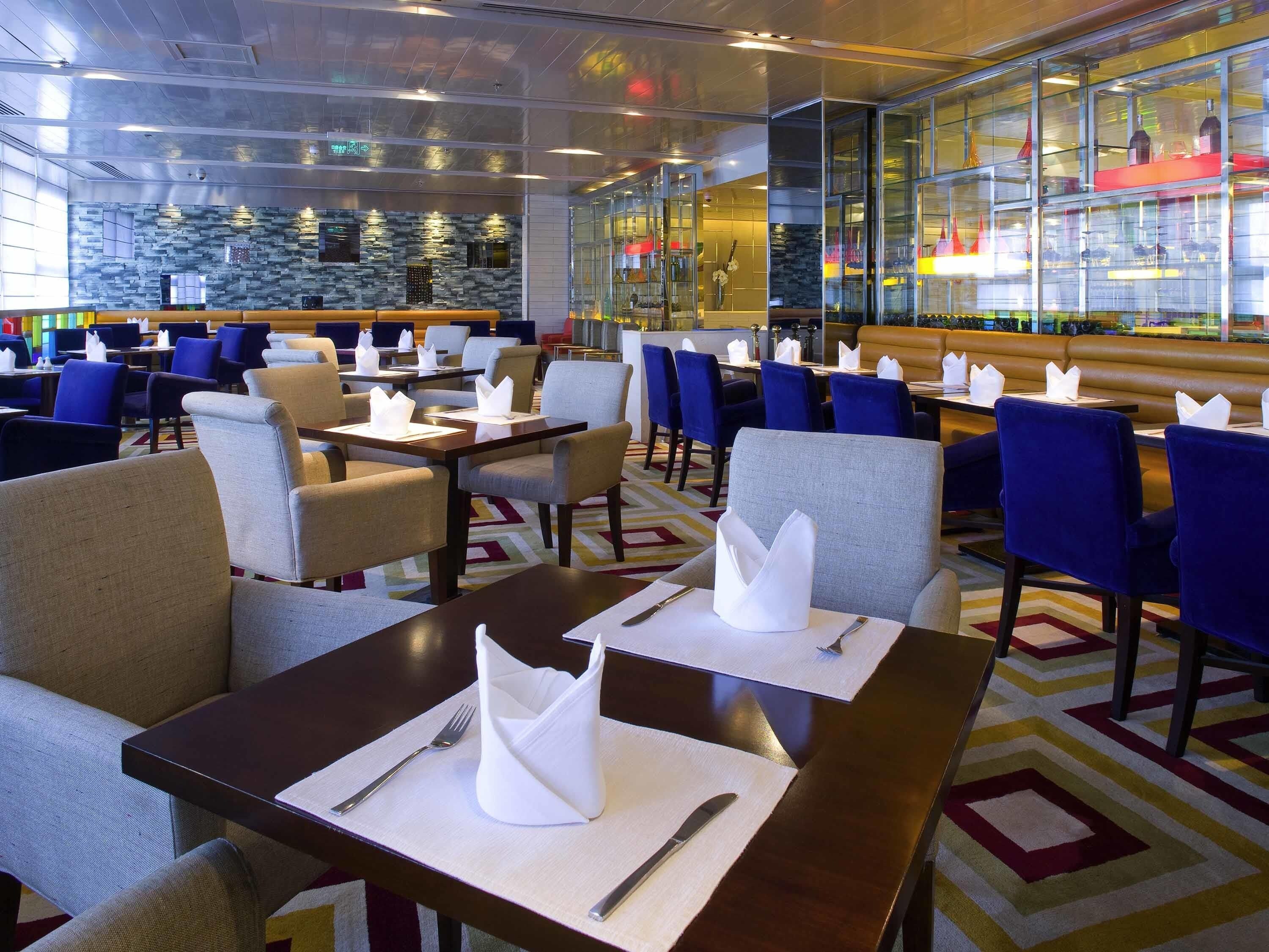 Un comedor de hotel con mesas, sillas y una barra.