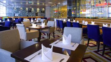 Un comedor de hotel con mesas, sillas y una barra.