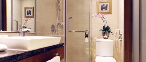 A modern bathroom with a glass shower enclosure, a white sink, and a toilet.