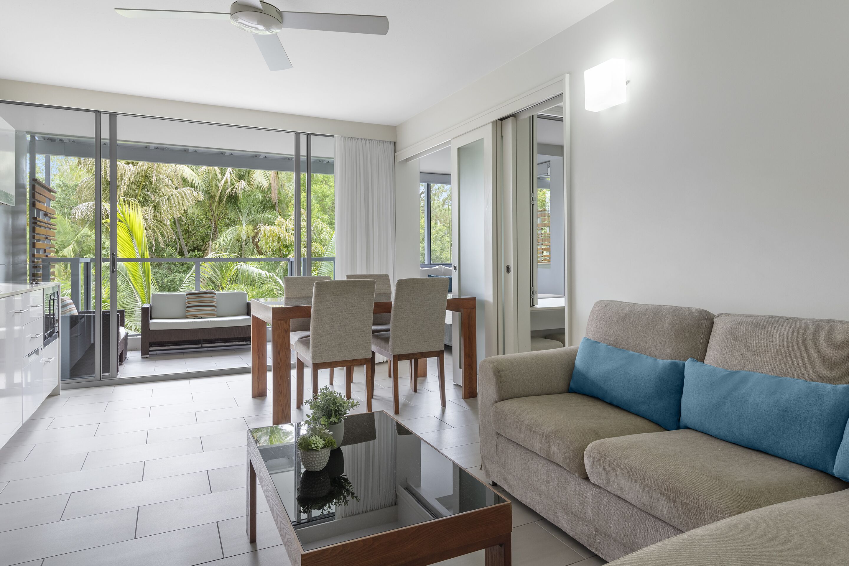 A modern living room with a sofa, a coffee table, and a dining area with chairs and a table.