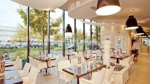 Een restaurant met grote ramen, witte stoelen en tafels.