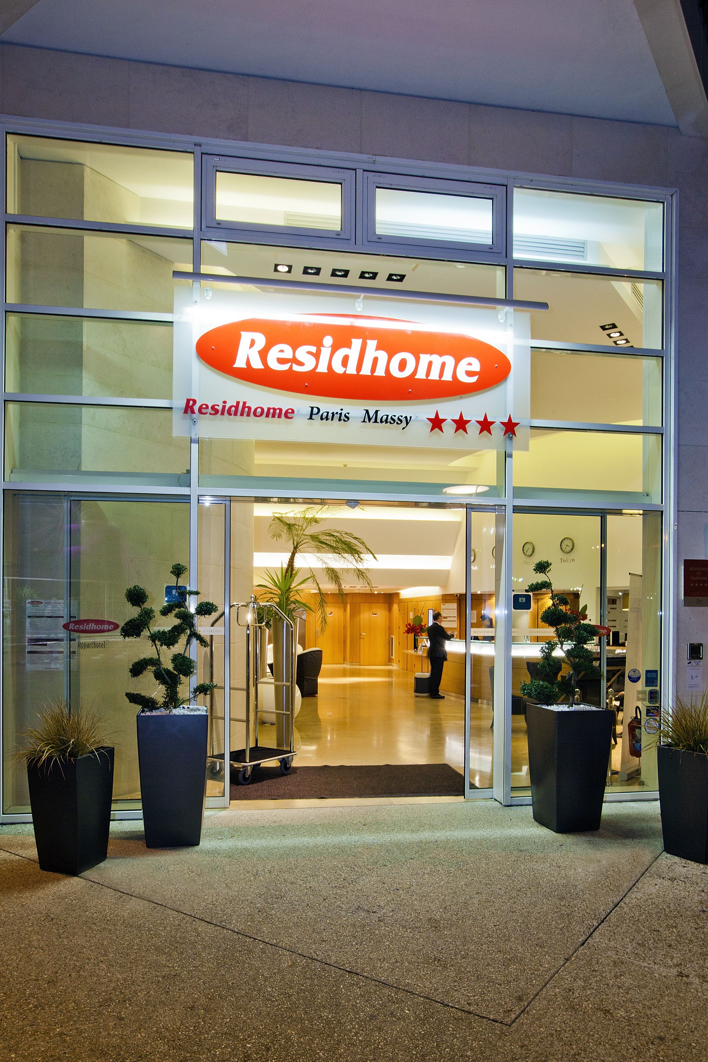 A hotel entrance with a sign reading "Residhome Paris Massy" and a reception desk inside.