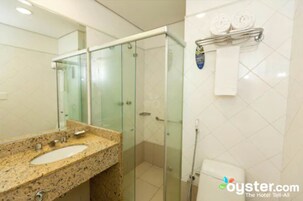 A bathroom with a granite countertop sink, a glass shower enclosure, and a towel rack with two towels.