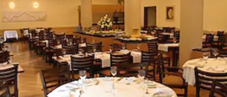 A dining area with round tables set for meals, chairs, and a central floral arrangement.