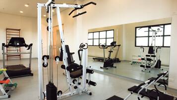 A gym with various exercise machines, a mirror, and a window.