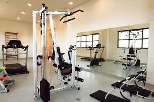 Una palestra con diverse macchine per esercizi, uno specchio e una finestra.