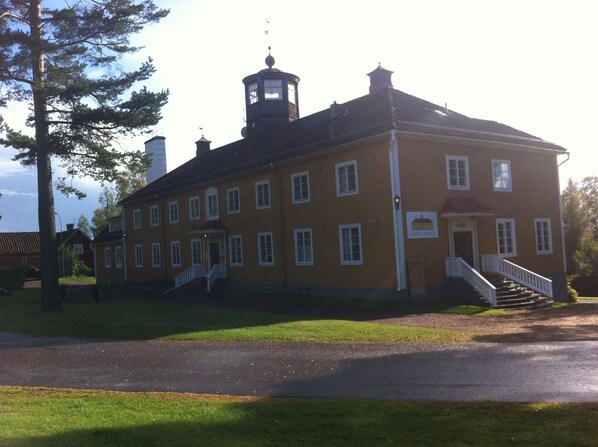 A two-story yellow building with a central staircase, a small tower, and a sign reading "Inn of the North". - Insjöns Hotell (Insjon)