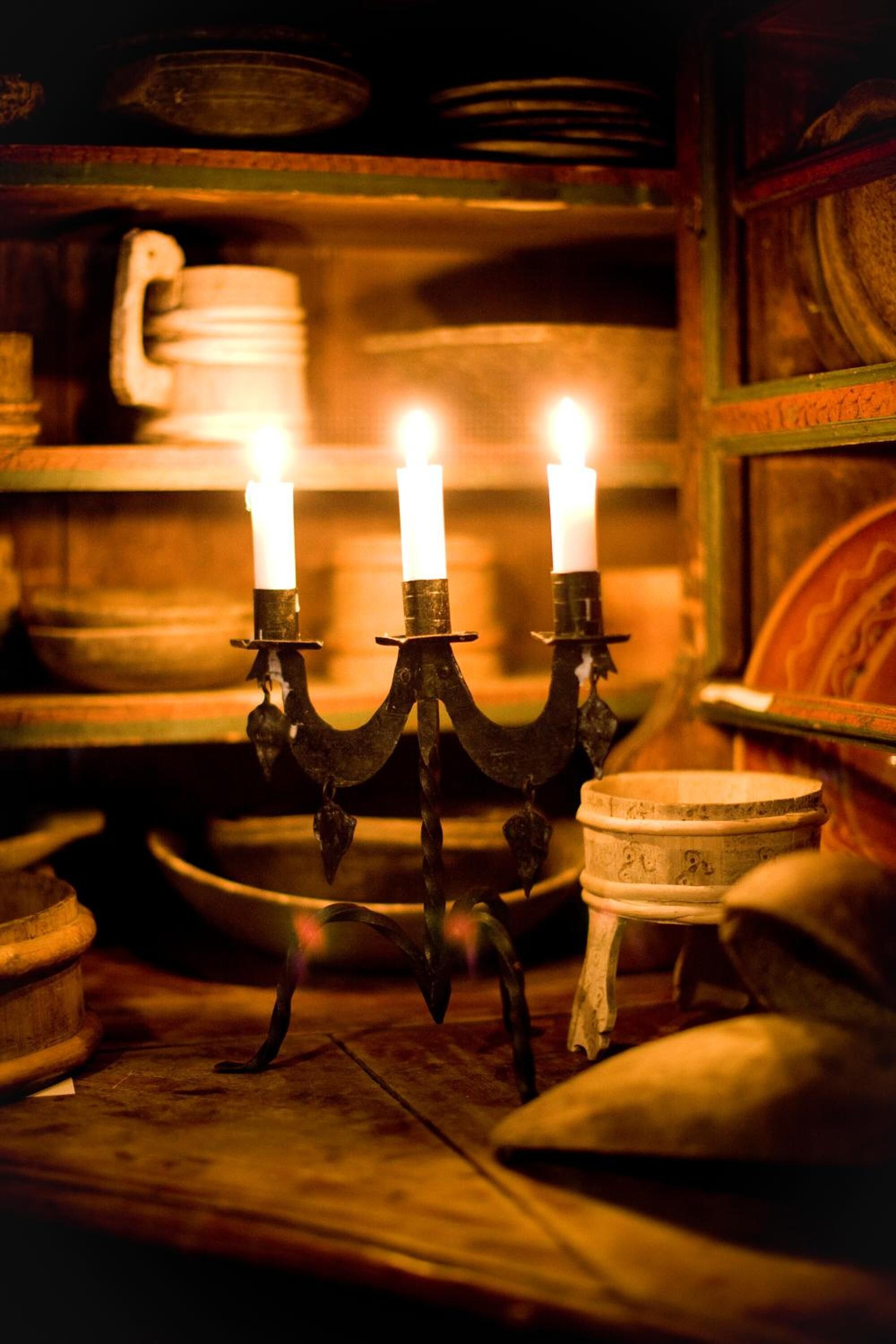Um candelabro com três velas acesas em um ambiente rústico.