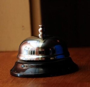 A black and silver bell with a reflective surface, placed on a wooden surface. - Insjöns Hotell (Insjon)