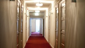 Ein Hotelkorridor mit rotem Teppich, Türen an beiden Seiten und einem Kronleuchter.
