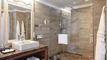 A modern bathroom with a marble sink, a glass-enclosed shower, and a large mirror.