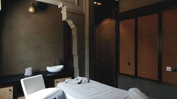 Features a large mirror, sink, and towel, with a textured wall pattern and a wooden panel.