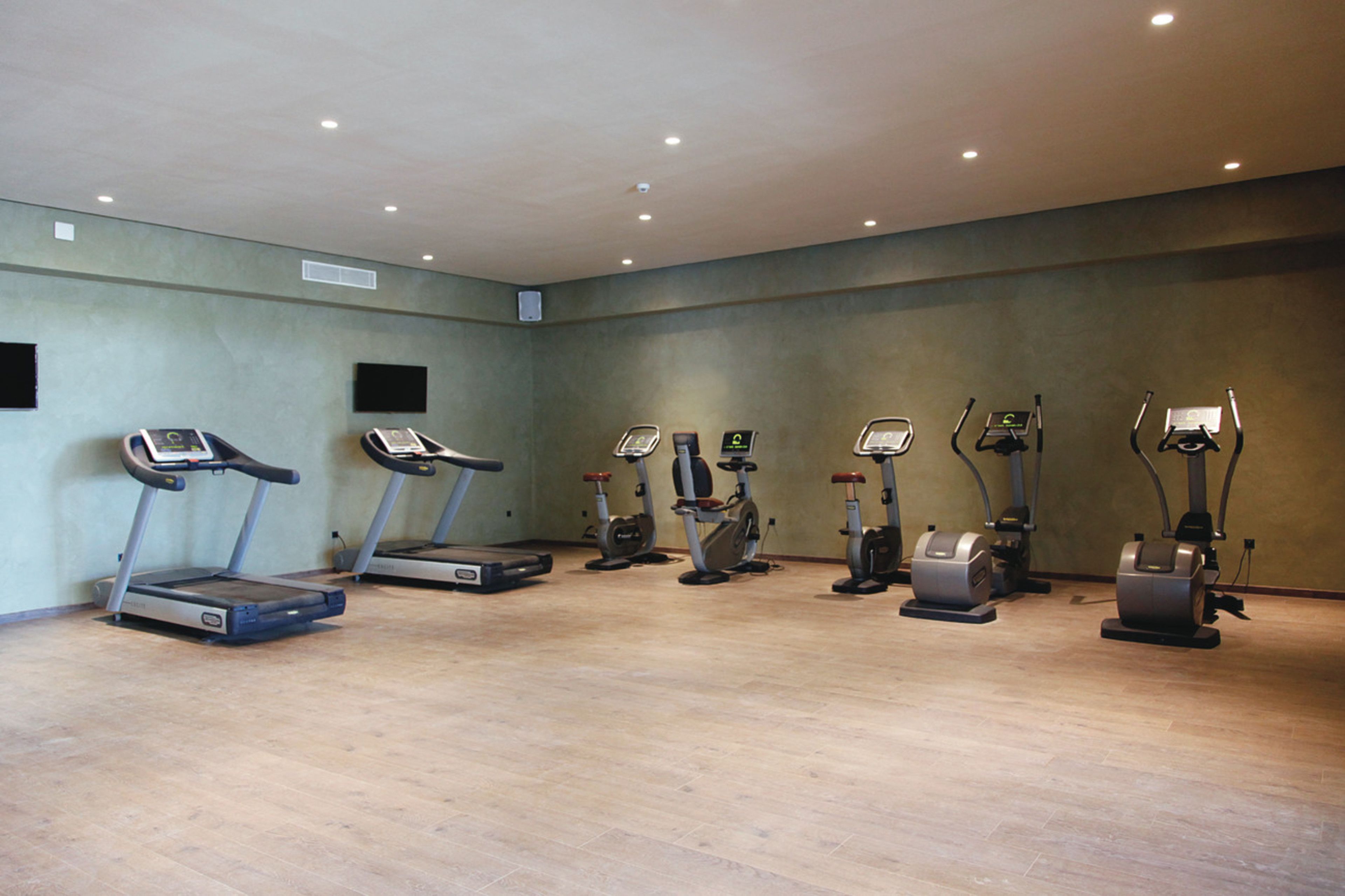 Un gimnasio con cintas de correr, bicicletas estáticas y máquinas elípticas.
