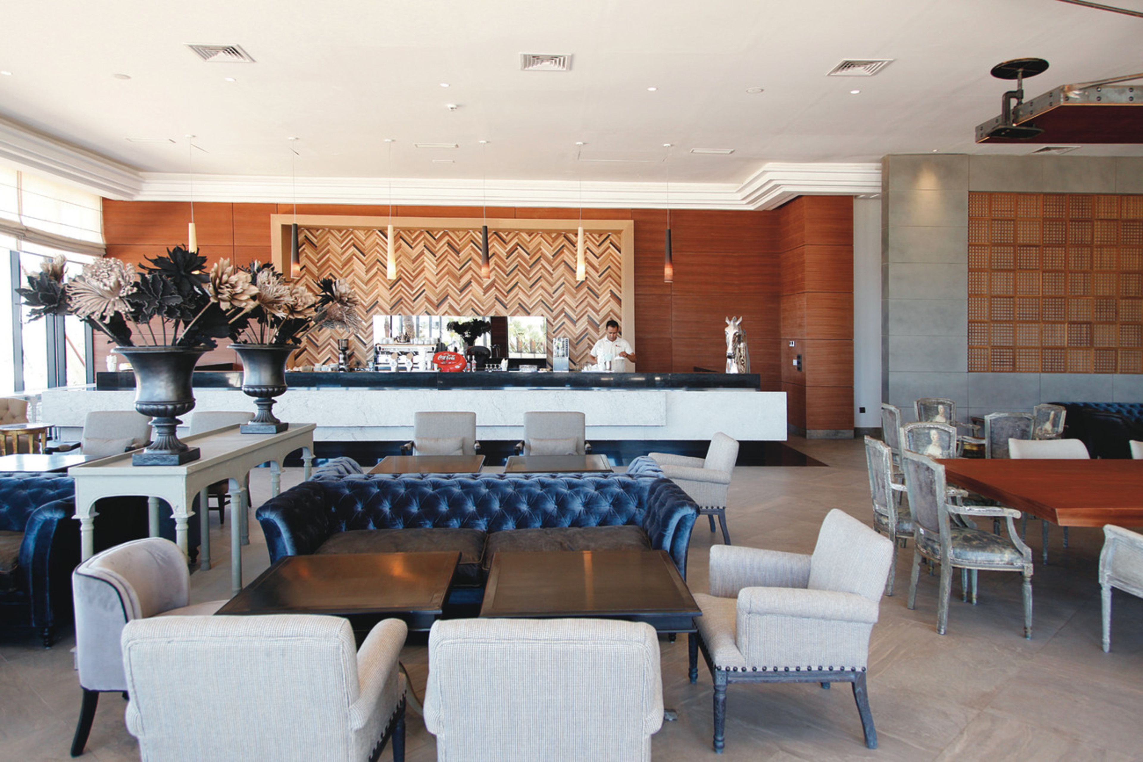 A spacious lobby with a central bar area, seating arrangements, and a decorative wall.