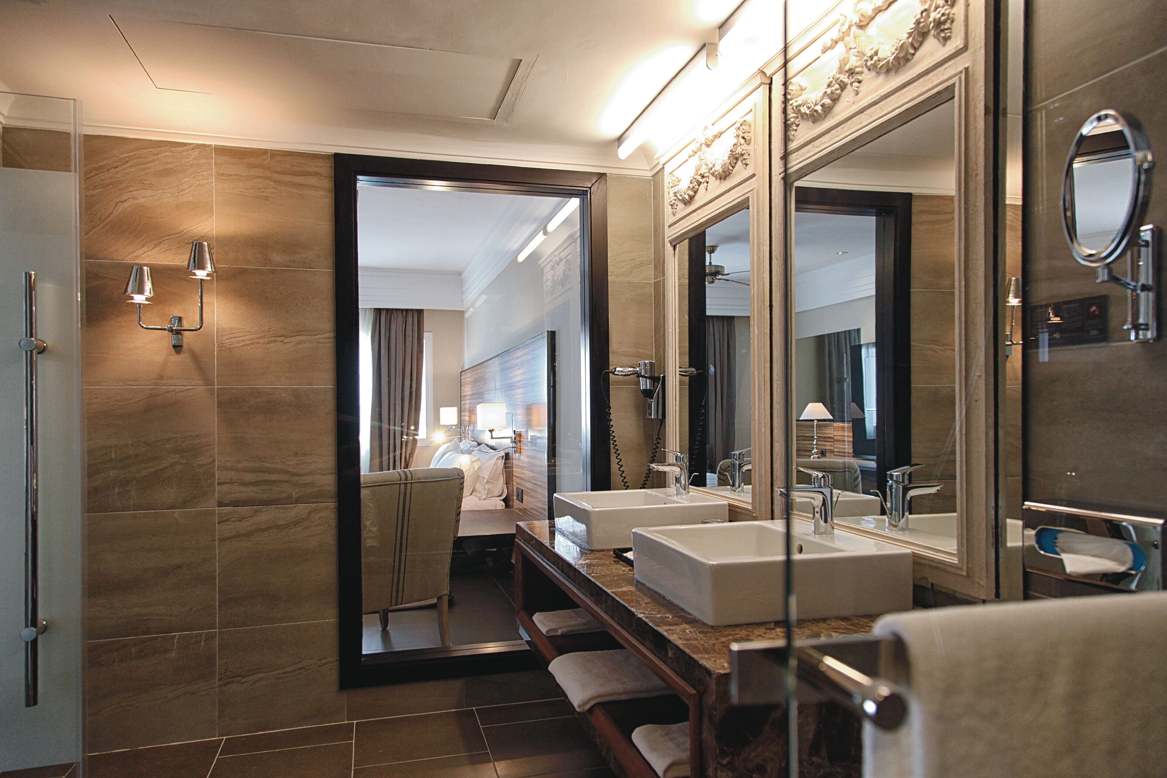 A modern bathroom with two sinks, large mirrors, and a shower area.