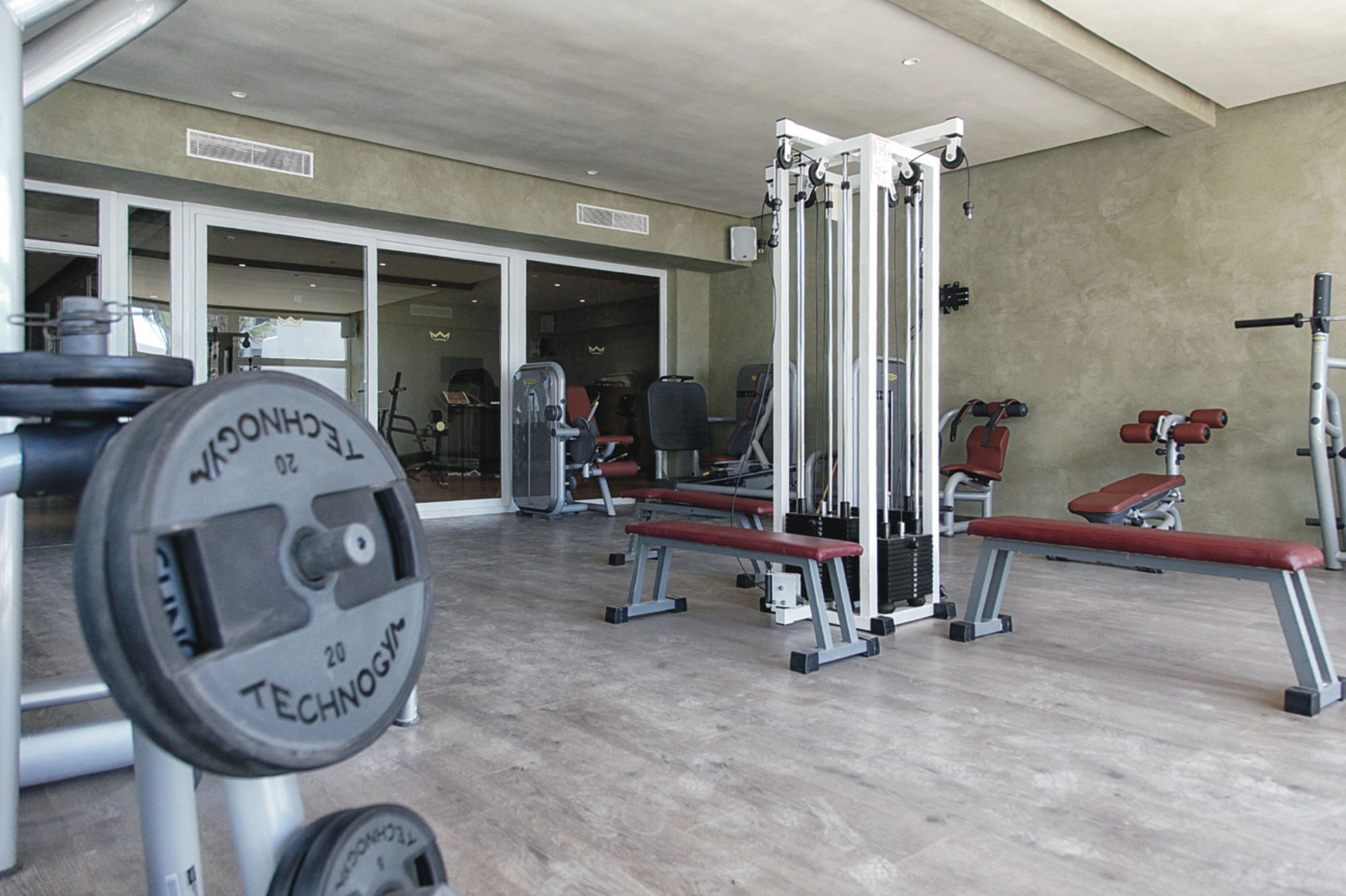 Une salle de sport équipée de matériel de musculation, de bancs et d’un mur recouvert de miroirs.