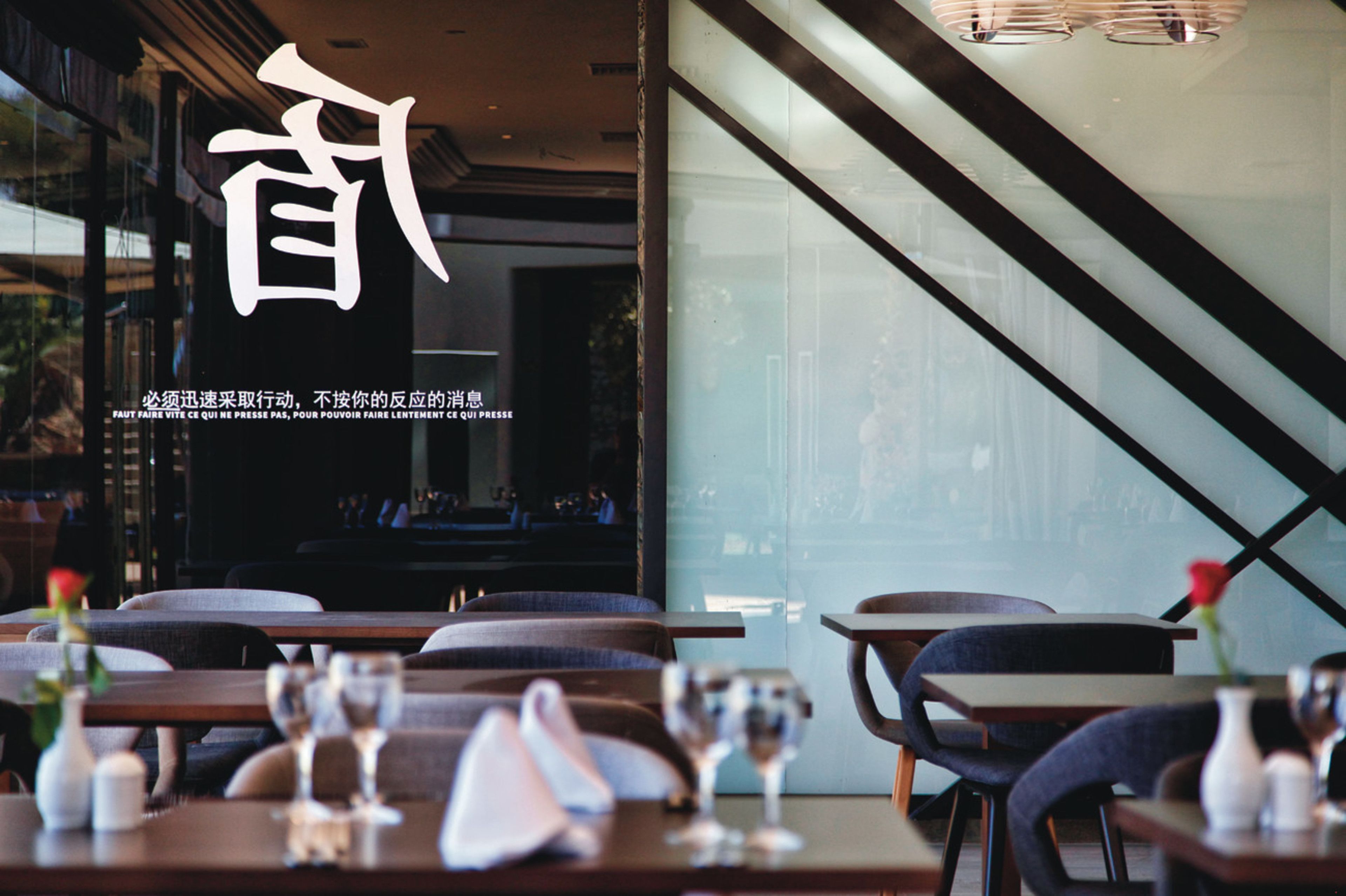 A modern restaurant interior with tables, chairs, and a glass partition.