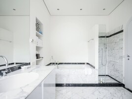 Un baño moderno con una bañera grande, una zona de ducha separada y un lavamanos con un lavabo y espejo.