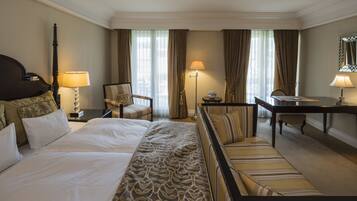 A hotel room with a large bed, a sofa, a desk, and a chair.