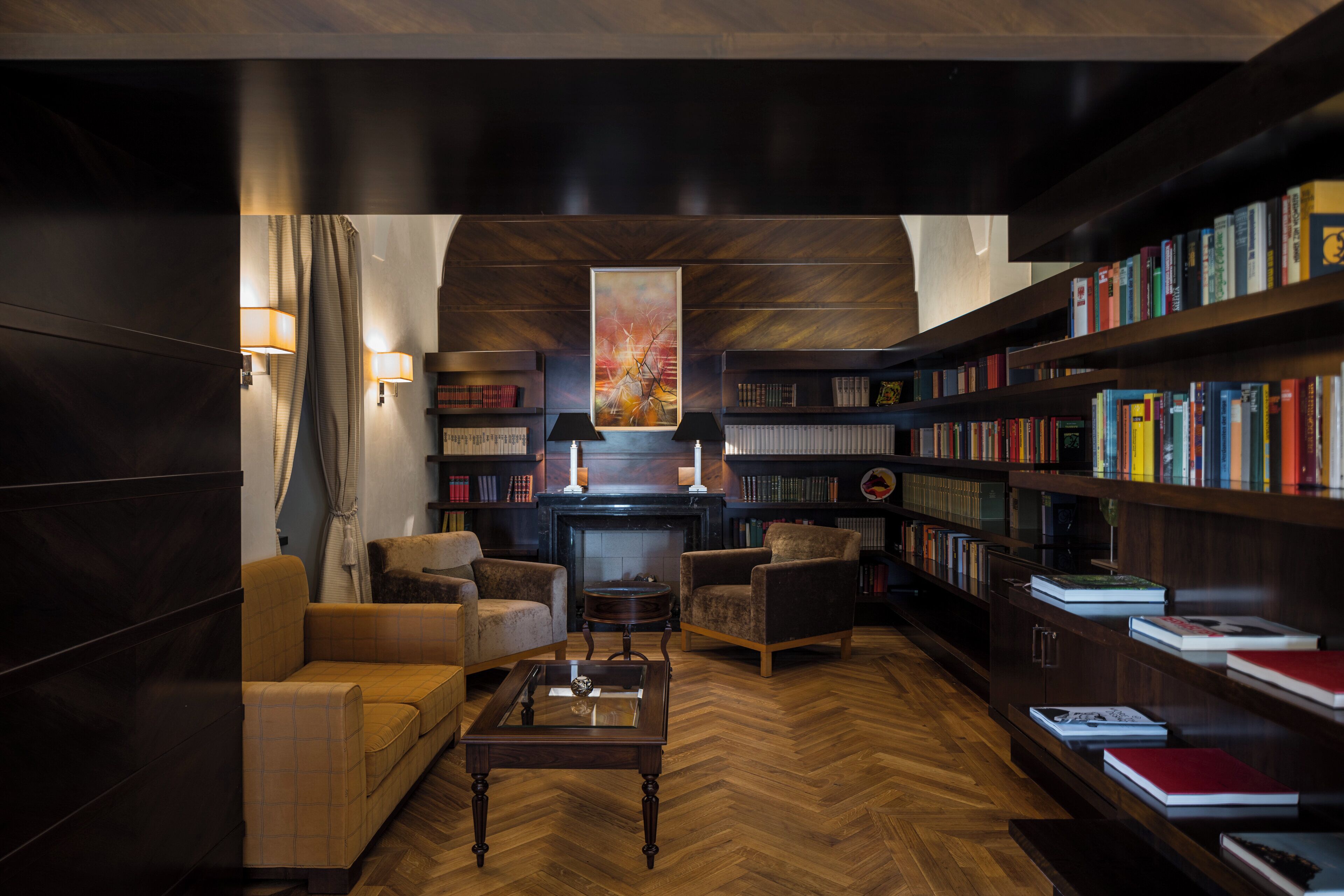 Eine Bibliothek mit Bücherregalen, einem Kamin und Sitzbereichen.