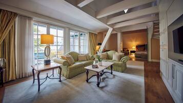 A spacious living room with a high ceiling, large windows, and a cozy seating area with a sofa and armchairs.