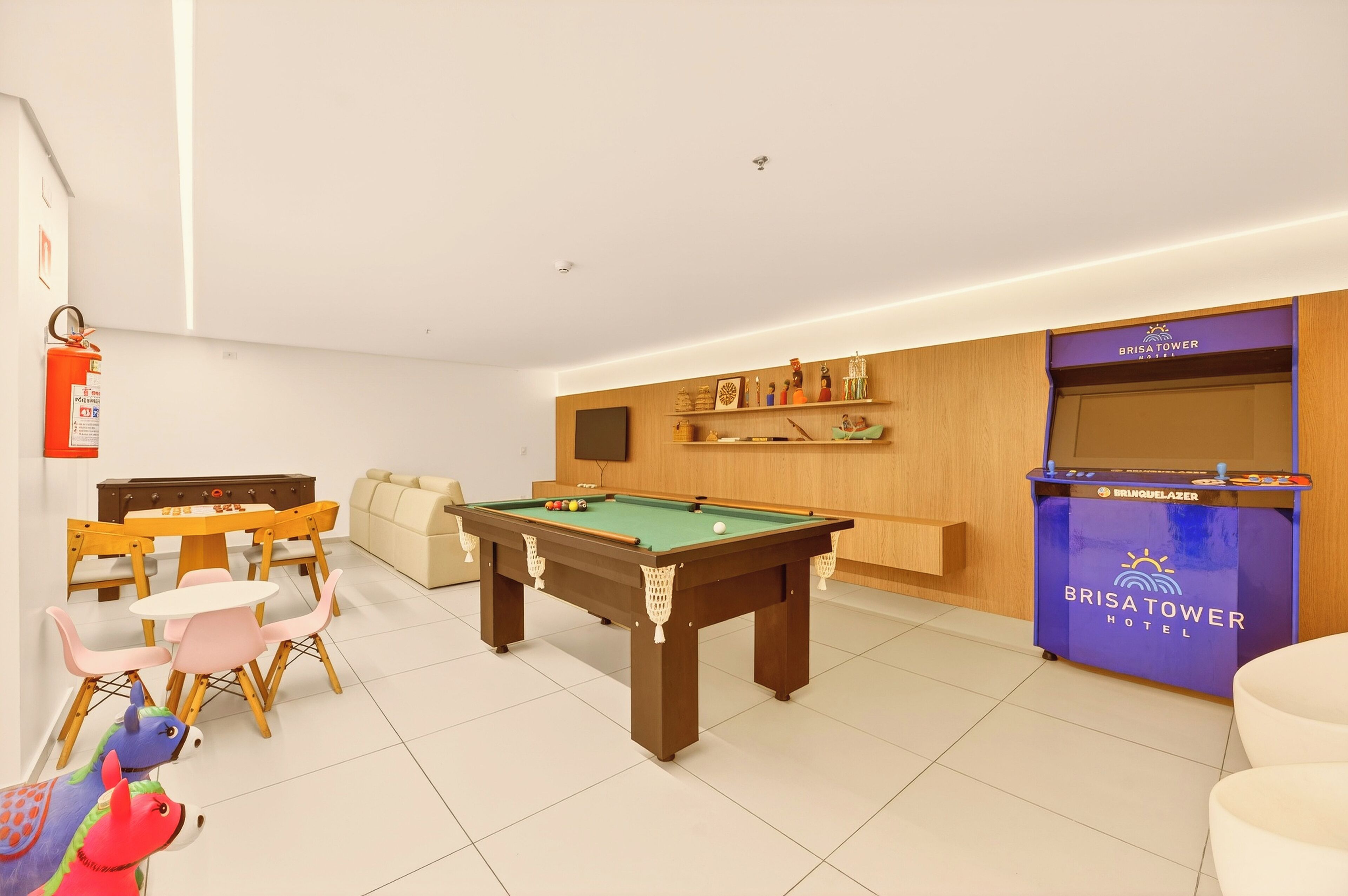 Una habitación de hotel con mesa de billar, sofá, mesa de comedor con sillas y un minibar.