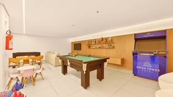 Una habitación de hotel con mesa de billar, sofá, mesa de comedor con sillas y un minibar.