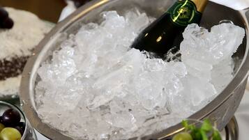 Un bol de hielo con una botella de champán y copas de uvas.