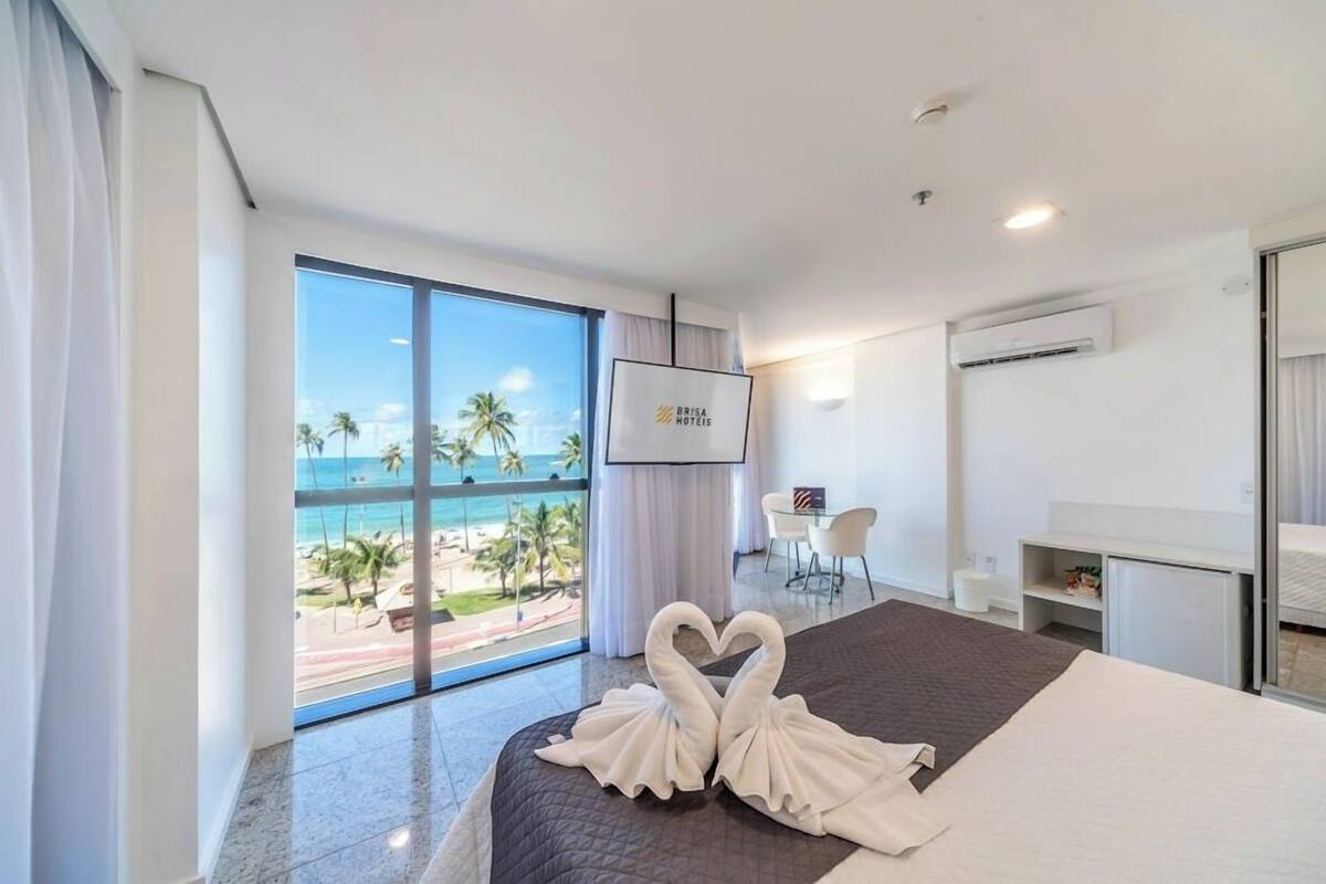 Una habitación de hotel con un amplio ventanal que ofrece vistas a la playa y al océano.