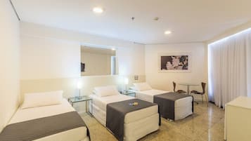 Habitación de hotel con dos camas, una mesita, una silla, un espejo y un cuadro en la pared.