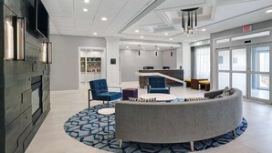 A modern lobby with a reception desk, seating area, and a fireplace.