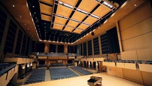 Un vaste auditorium doté de gradins, d’une scène centrale et d’un grand plafond au décor géométrique.