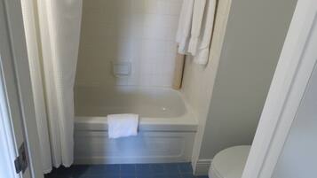 Un baño con bañera, inodoro y cortina de ducha.
